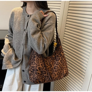 Detail of leopard print tote bag featuring brown faux leather strap and long side tassels