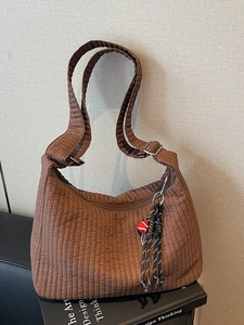 Brown quilted tote bag with pleated texture and sporty tennis racket charm accessory
