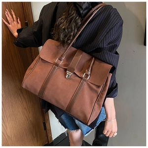 Vista dettagliata di una grande borsa tote vintage marrone indossata a spalla con fibbia