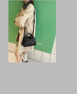 Model showcasing a large black leather Boston tote bag with metal ring detail