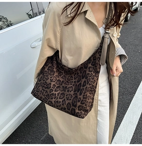 Close-up of leopard print tote bag with adjustable strap worn with a beige trench coat