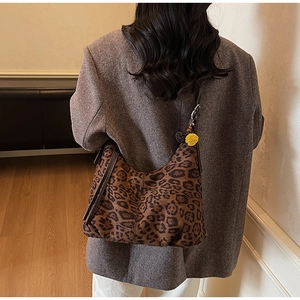 Detail of leopard print hobo shoulder bag with a yellow charm on a grey blazer model