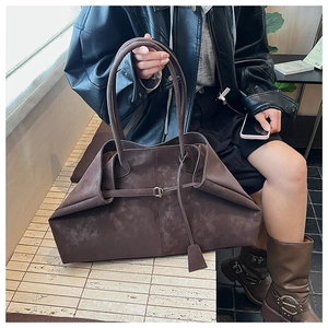 Detail of dark brown matte leather tote bag with stylish metal buckle and long handles