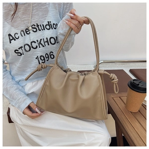 Detail of the soft pleated leather texture and stylish knotted handle on a beige cloud bag