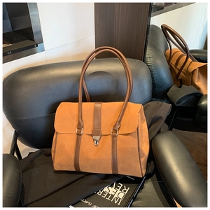 Dettaglio borsa tote in pelle scamosciata marrone con finiture in pelle e chiusura in metallo