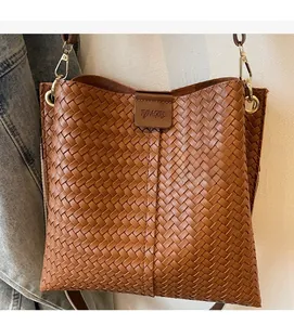 Dettaglio della trama in pelle intrecciata marrone e logo su una borsa stile retrò