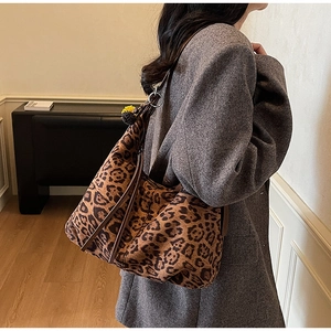 Detailed view of leopard print shoulder bag with plush ball charm and leather strap
