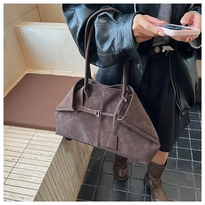 Detail of a large brown matte leather tote bag with metallic buckle and slim straps