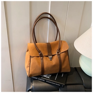 Dettaglio macro della borsa tote in pelle scamosciata caramello con fibbia e cinturini in pelle