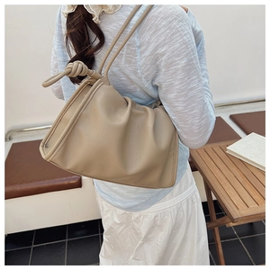 Close-up of a soft beige pleated cloud bag with a decorative knotted shoulder strap