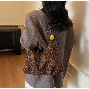 Detail of leopard print hobo bag with brown leather strap and yellow pompom charm
