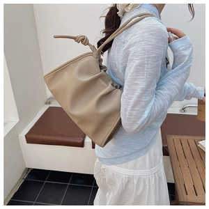 Detail of soft pleated cloud bag in beige leather with stylish knotted shoulder strap