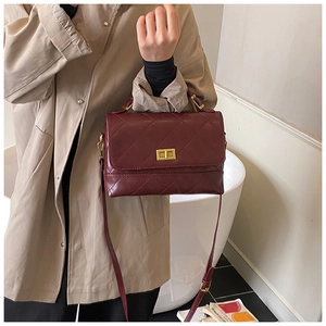 Mannequin portant un sac à main matelassé bordeaux avec fermoir doré et bandoulière