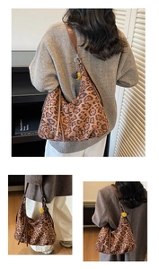 Detail of leopard print underarm bag featuring a stylish brown strap and pompom charm