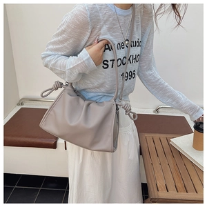 Detail view of the soft pleated dumpling bag featuring a unique knotted shoulder strap