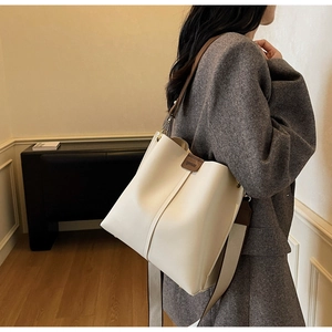 Dettaglio della borsa a secchiello beige minimalista con finiture in pelle marrone
