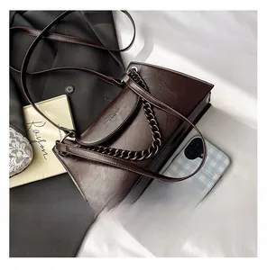 Close-up of a dark brown square bag featuring vintage chain and glossy leather texture