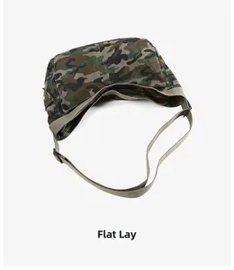 Flat lay of camo canvas crossbody bag with wide adjustable strap and crescent shape
