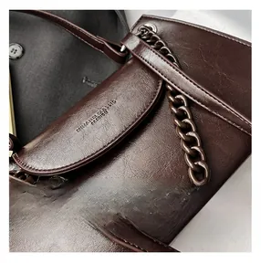 Detailed close-up of dark brown cracked faux leather texture and embossed logo on bag