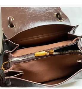 Detail of smooth gold metal zipper and dark brown leather texture on handbag