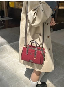 Detail of red vintage boston bag with brown leather patchwork and golden hardware