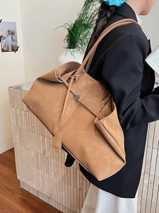 Minimalist camel suede tote bag with drawstring details shown in a modern lifestyle setting