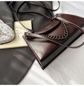 Detail of dark brown oil wax leather shoulder bag with metallic chain and long strap