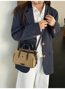 Model wearing a khaki canvas tote bag with brown leather trim and cross-body strap