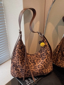 Vintage leopard print shoulder bag with brown leather strap and decorative fur pom-poms