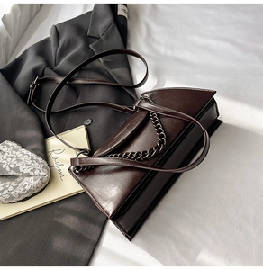 Detail of vintage dark brown faux leather bag with bronze chain strap and flap closure