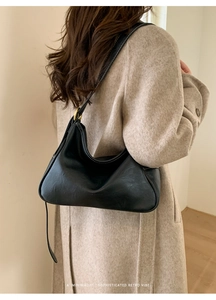 Detail of minimalist black hobo bag with contrast white stitching and bronze buckle