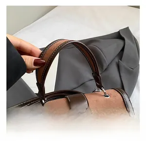 Dettaglio del manico della borsa in pelle scamosciata con cuciture a contrasto bianche