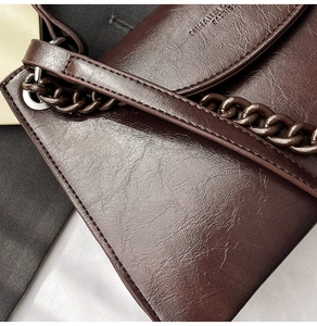 Detail of dark brown vintage faux leather texture with chain strap and embossed logo