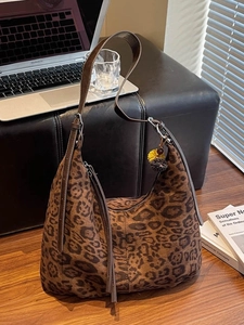 Vintage leopard print shoulder bag with tassel and pom-pom detail in a stylish cafe setting