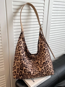 Large leopard print tote bag with adjustable leather strap on a minimalist background