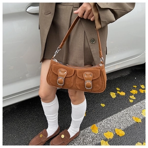 Detail der braunen Wildleder-Baguette-Tasche mit doppelten Klappentaschen und Metallteilen