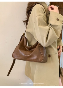 Detail showing vintage brown leather shoulder bag with pleated base and strap buckle