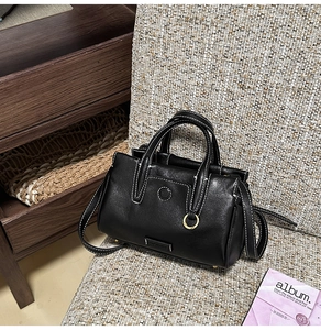 Detail of black leather Boston bag with white contrast stitching and silver ring ornament