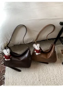 Detail view of vintage hobo underarm bags in brown tones with white bear charms on soft rug