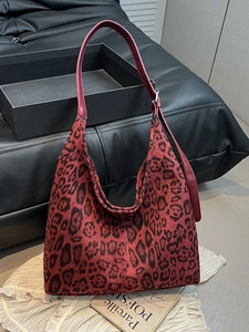 Large red leopard print hobo bag with adjustable leather strap on a white fabric surface