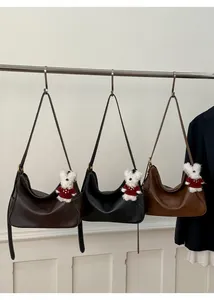 Three minimalist underarm bags in dark brown, black, and light brown with bear charms