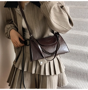 Retro brown leather baguette bag with thick chain handle shown on a model