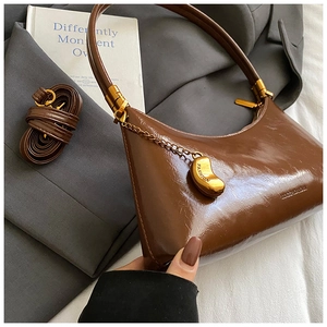 Détail du sac vintage en cuir marron brillant avec pendentif doré et bandoulière