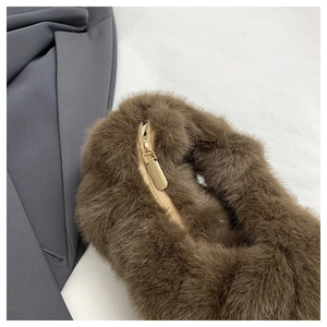 Détail de la fermeture éclair dorée et de la peluche marron douce sur un sac à main