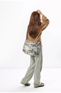 Rear view of a model wearing the large grey camouflage canvas messenger bag with strap