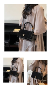 Detail view of black split-texture crossbody bag with golden twist lock and round handle