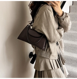 Close-up of a dark coffee leather square bag with thick chain detail and shoulder strap