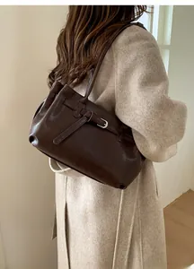 Detail of dark brown tote bag featuring vintage silver buckle on beige wool coat