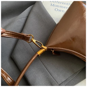 Détails des ferrures en bronze vintage et texture cuir huilé brillant du sac marron foncé