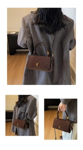 Detail of vintage brown suede leather box bag featuring a gold oval twist lock and handle